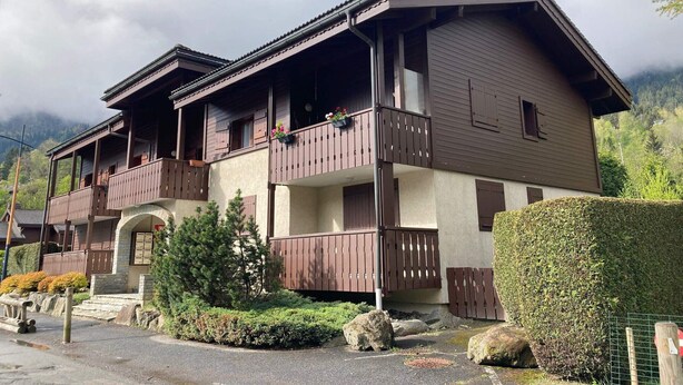 Un chalet à deux étages doté de balcons en bois et d’une entrée en pierre.