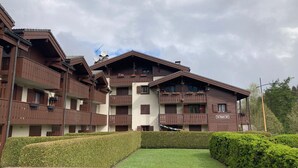 Un immeuble à plusieurs étages doté de balcons, une enseigne indiquant « Les Sarras », et une pelouse bien entretenue à l’avant.