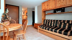 Un espace de vie compact comprenant une table à manger, des chaises, un canapé et des meubles en bois.