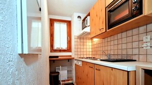 Une cuisine compacte avec des meubles en bois, un four à micro-ondes, une cuisinière et un dosseret carrelé.