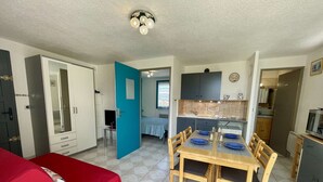 A compact living space with a dining area, kitchenette, and a bedroom.