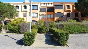 A multi-story residential building with a central courtyard, surrounded by well-maintained hedges and trees.