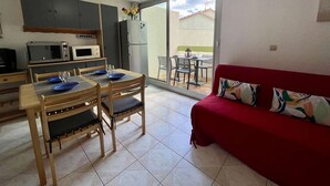 A compact living space with a dining area, kitchenette, and a red sofa.