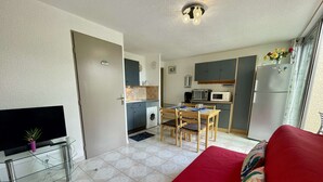 A compact living space with a kitchenette, a dining area, and a seating area with a red sofa.