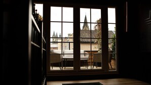 A room with a large window overlooking a courtyard with a traditional building and a church spire. - Gorgeous home in Roermond with kitchen (Roermond)
