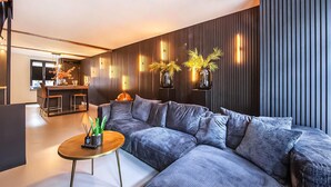 A modern living room with a sectional sofa, a small round coffee table, and a kitchen area in the background. - Gorgeous home in Roermond with kitchen (Roermond)