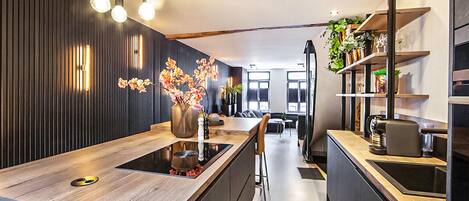 A modern kitchen with a central island, pendant lighting, and a view into the dining area.