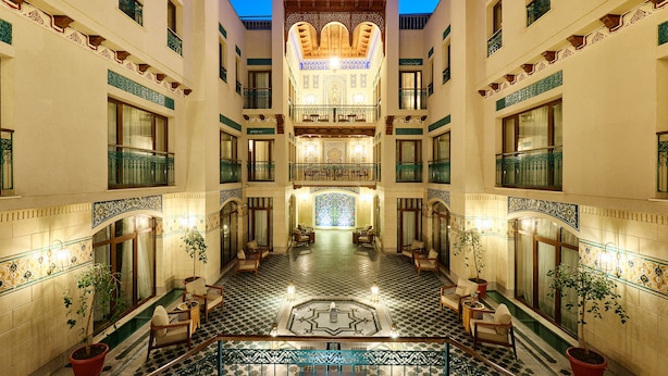 A grand hotel lobby with a checkered floor, ornate balconies, and a central decorative area. - Kosh Havuz Boutiqe Hotel (Samarkand)
