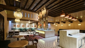 A restaurant with a central counter, multiple seating areas, and patterned flooring. - Kosh Havuz Boutiqe Hotel (Samarkand)