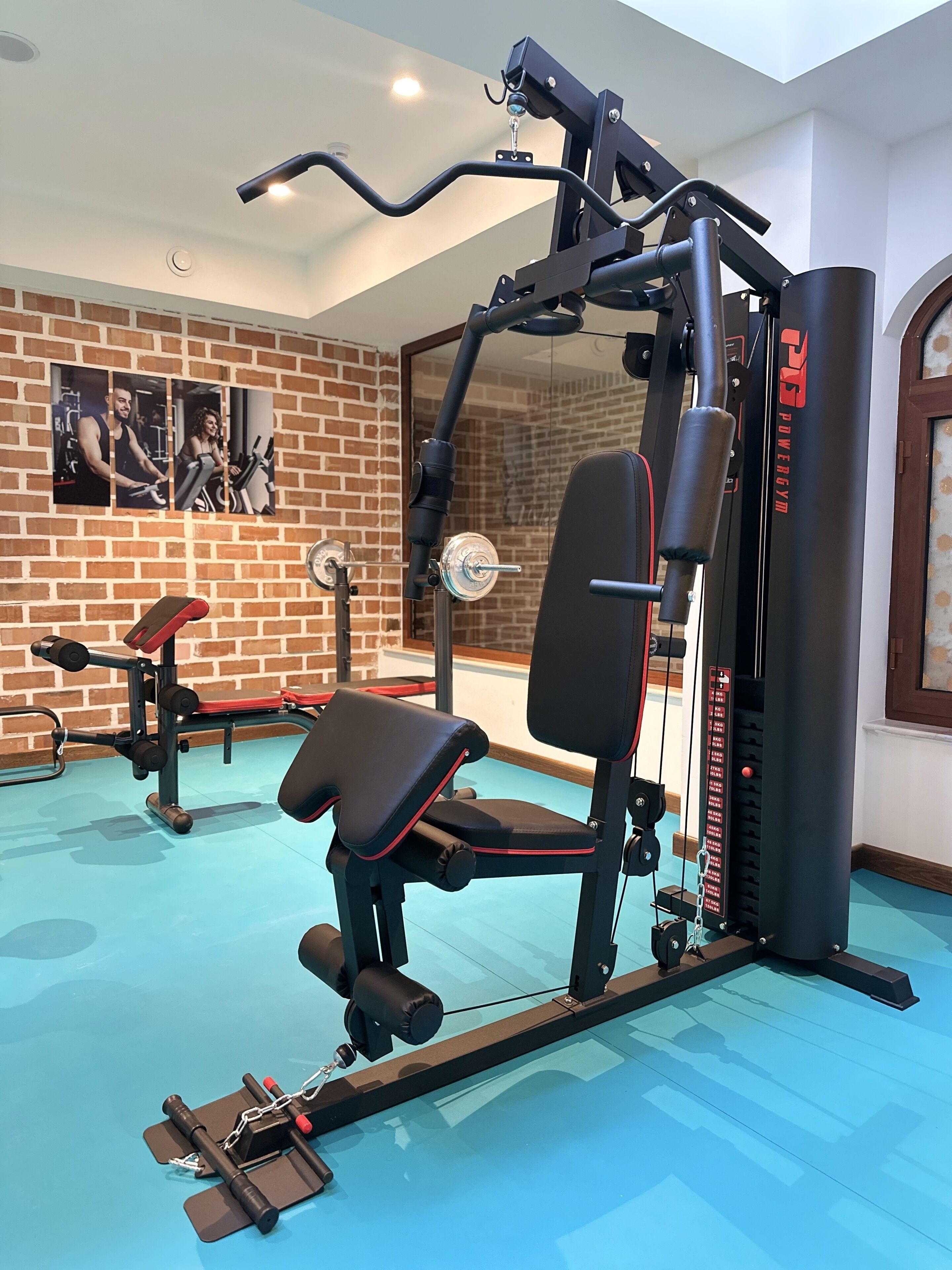 Ein Fitnessraum mit Trainingsgeräten, einer Bank und einer Ziegelwand mit gerahmten Bildern.