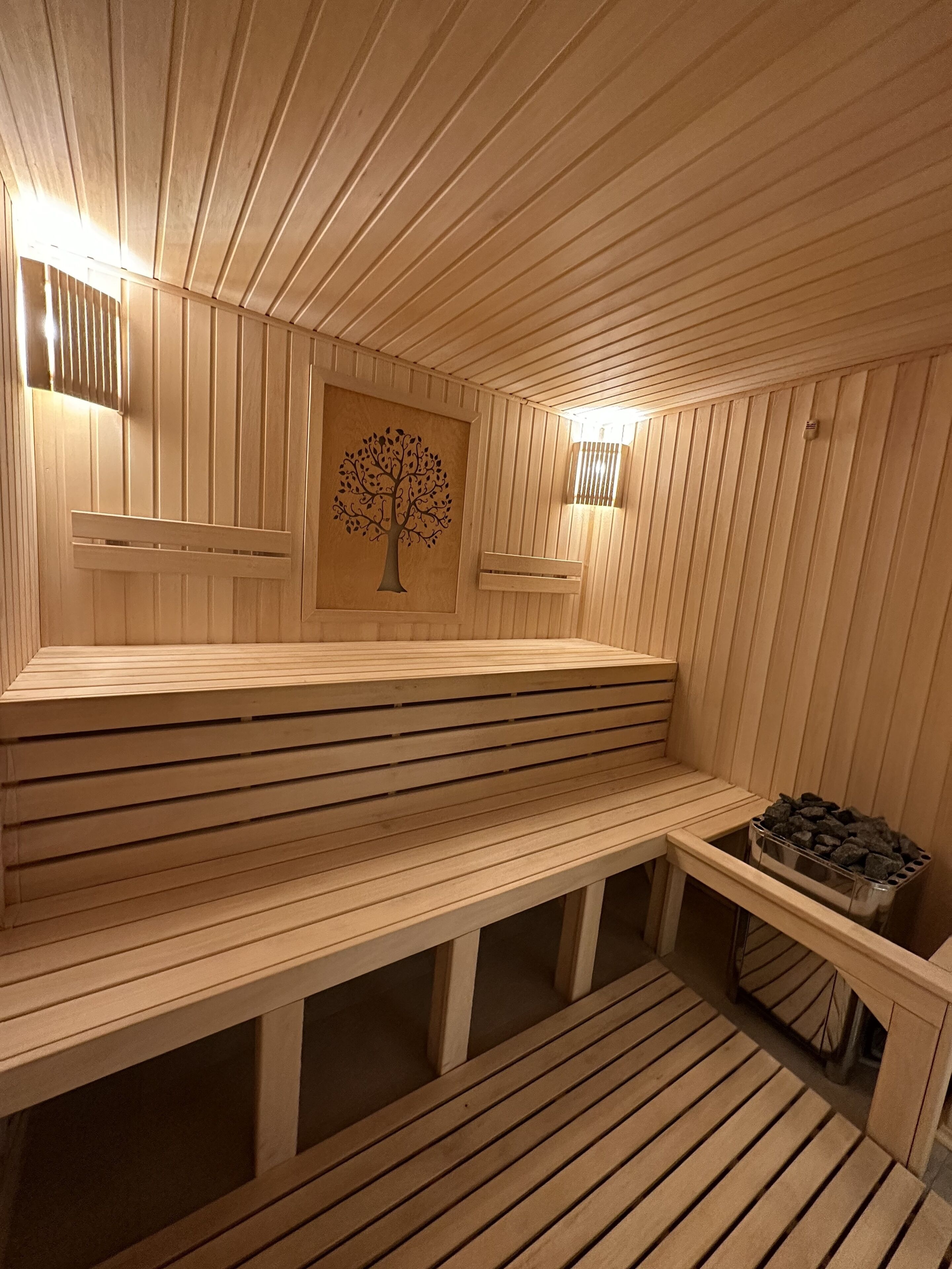 Una sauna con bancos de madera y un calentador fijado a la pared.