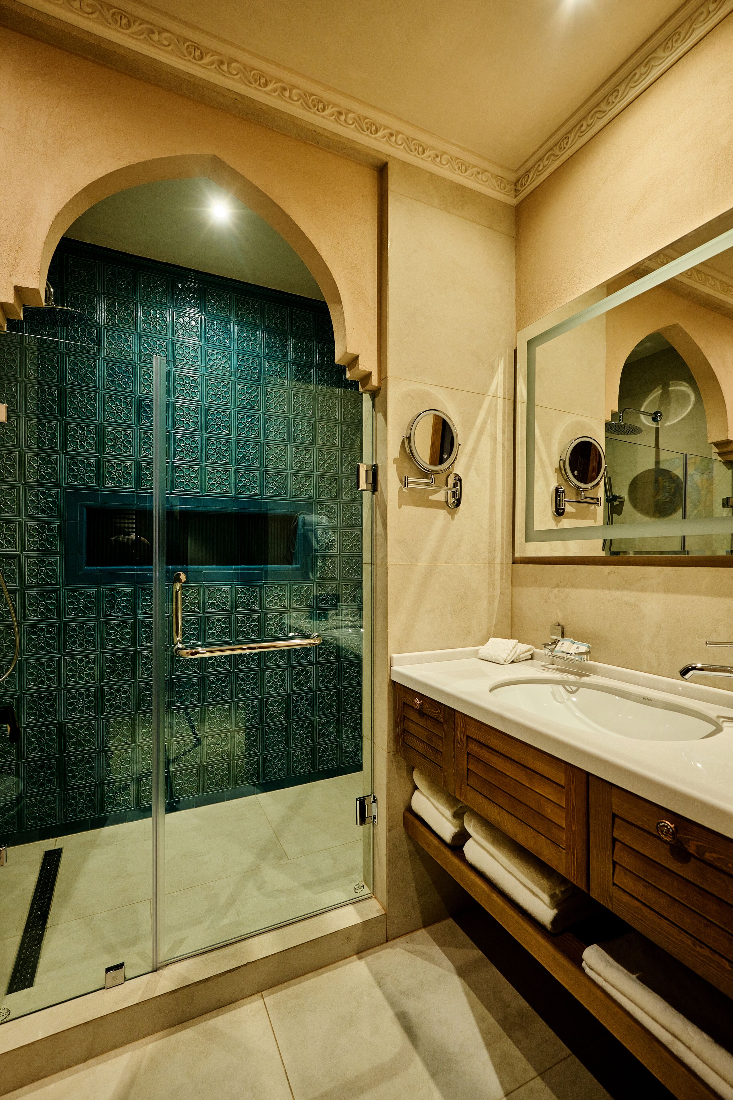 A bathroom with a glass-enclosed shower, a vanity with a mirror, and a towel rack.