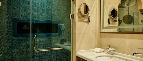 A bathroom with a glass-enclosed shower, a vanity with a mirror, and a towel rack.