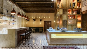 A bar area with a marble counter, wooden chairs, and hanging pendant lights. - Kosh Havuz Boutiqe Hotel (Samarkand)