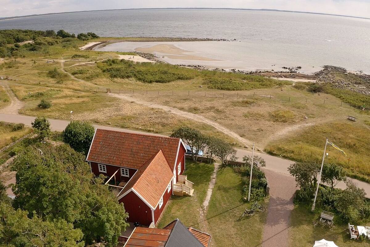 Ein Küsteneigentum mit einem roten Gebäude, einem Sandstrand und freiem Blick auf das Meer.