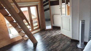 Een kamer met een houten vloer, een witte deur en een raam.