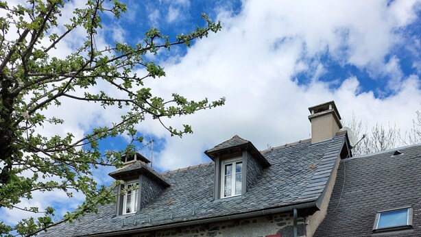 A stone building with red shutters, multiple windows, and a sloped roof. - Proche Laguiole - Maison au Calme - vue Imprenable (Curières)