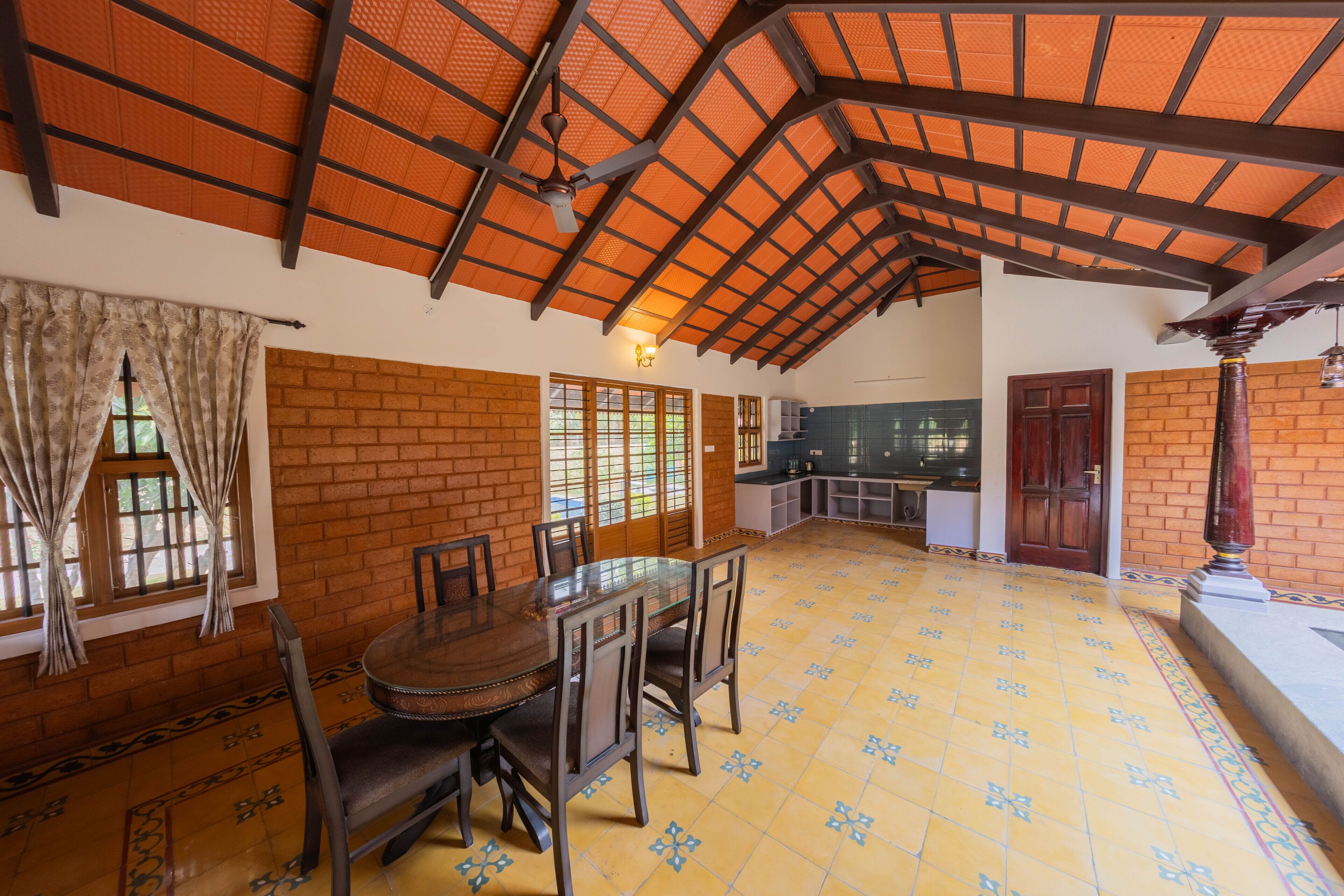 A spacious dining area with a high ceiling, brick walls, and a tiled floor.