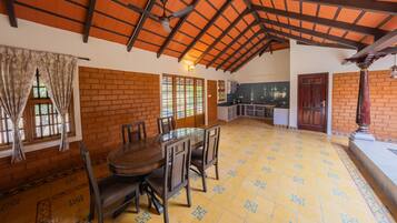 A spacious dining area with a high ceiling, brick walls, and a tiled floor.