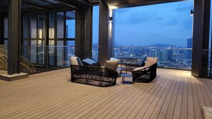 Un balcón moderno con mobiliario de mimbre y vistas a la ciudad.