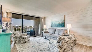 Una sala de estar con un sofá, dos sillones, una mesa de centro y un balcón con vistas.