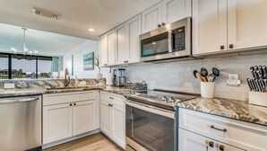 Cocina moderna con armarios blancos, electrodomésticos de acero inoxidable y encimera de mármol.