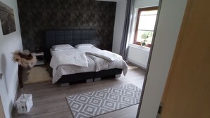 Quarto com cama, mesa de cabeceira, luminária e janela.
