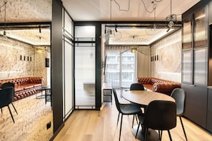 Un intérieur moderne avec une table à manger en bois, des chaises noires, un canapé en cuir et une grande fenêtre offrant une vue dégagée.