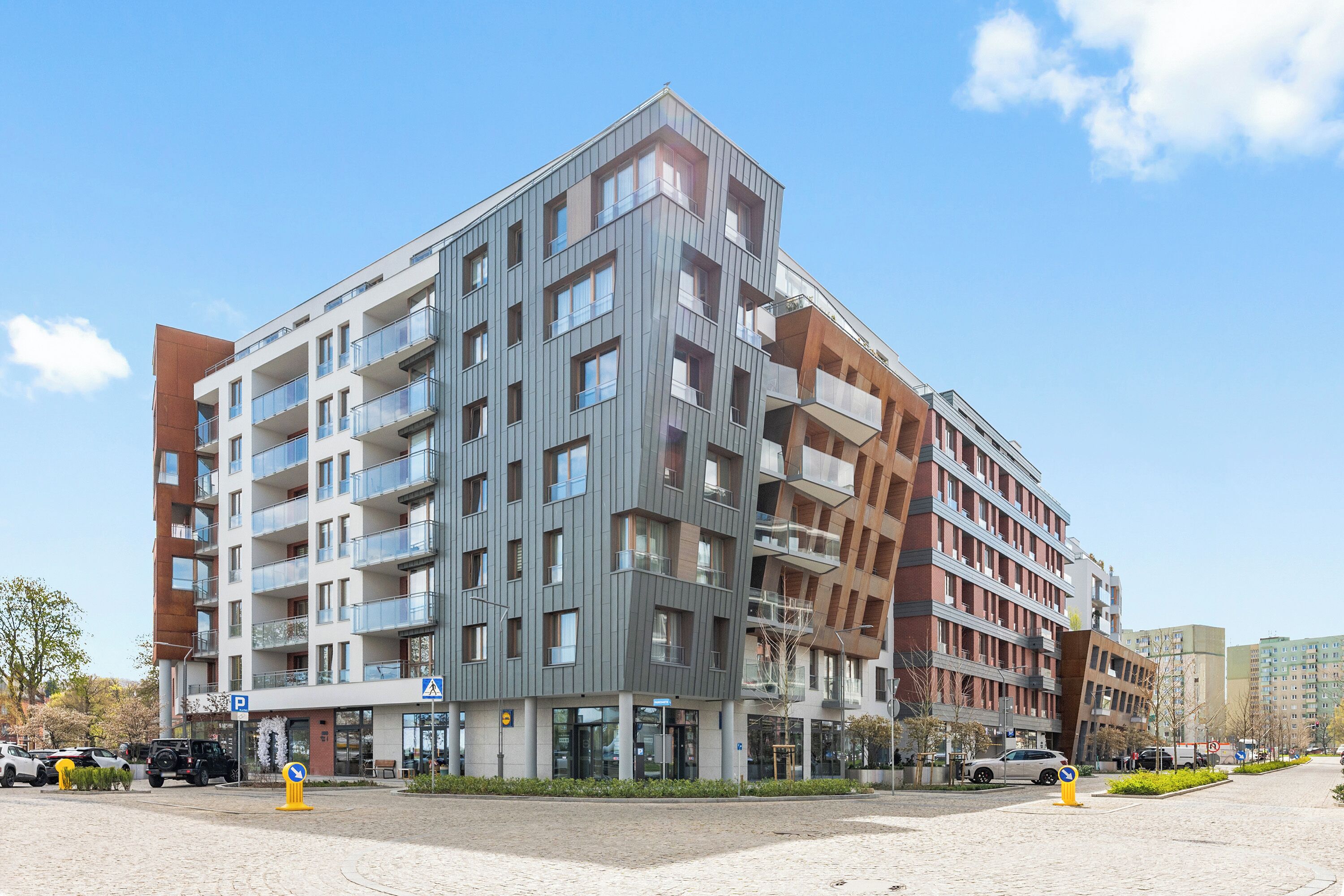 A multi-story hotel with balconies, a parking area, and a clear sky.