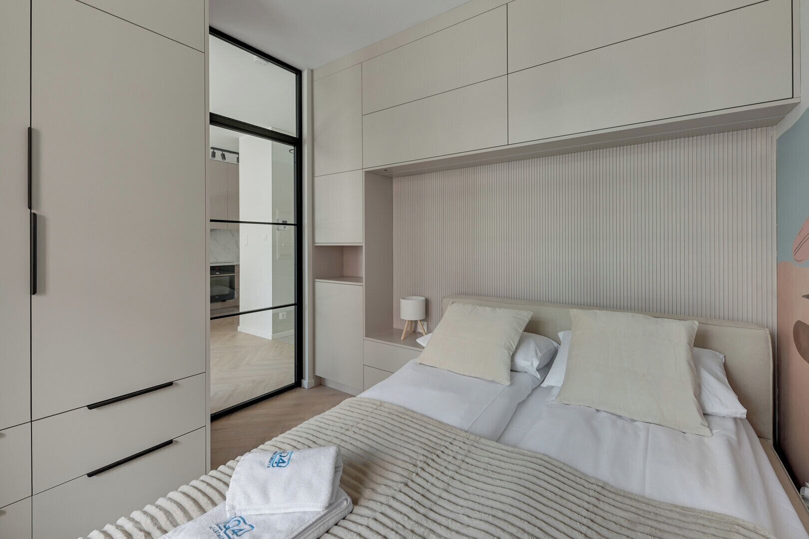 Ein modernes Schlafzimmer mit Bett, Nachttisch, Spiegel und Kleiderschrank.