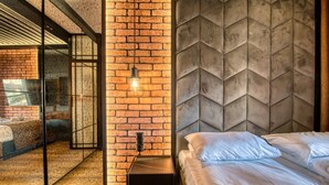 A modern bedroom with a brick wall, a geometric-patterned headboard, and a glass partition.