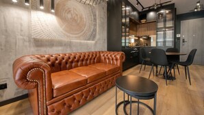 A modern kitchen with a dining area, featuring a leather sofa, a round table, and pendant lighting.