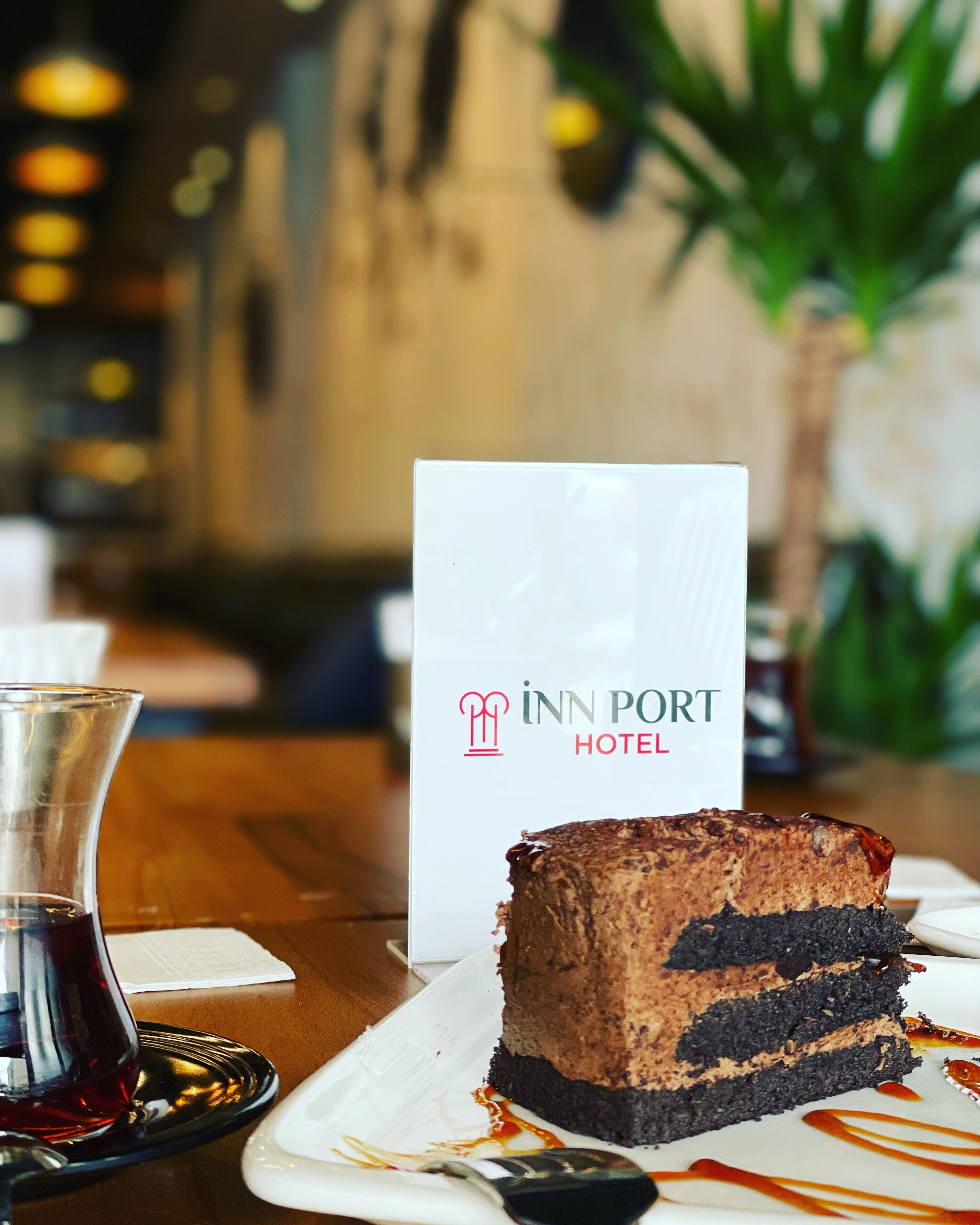 Una porción de pastel de chocolate con una etiqueta blanca que dice "Inn Port Hotel" sobre una mesa.