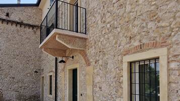 A stone building with a balcony, multiple windows, and a tiled courtyard.