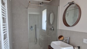 A modern bathroom with a glass-enclosed shower, a wooden vanity with a sink, and a mirror above the vanity. - CasaOssan (San Pietro in Cariano)