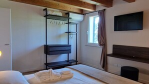 A room with a wooden ceiling, a bunk bed, a desk, a TV, and a window with curtains. - CasaOssan (San Pietro in Cariano)