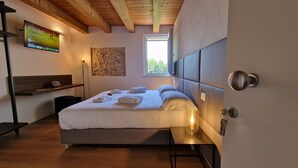 A modern bedroom with a bed, bedside table, and a TV mounted on the wall. - CasaOssan (San Pietro in Cariano)