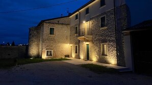 A stone building with a balcony, a door, and a small window. - CasaOssan (San Pietro in Cariano)