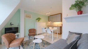 Um apartamento moderno com área de refeições, sala de estar com sofá, televisão e cozinha.