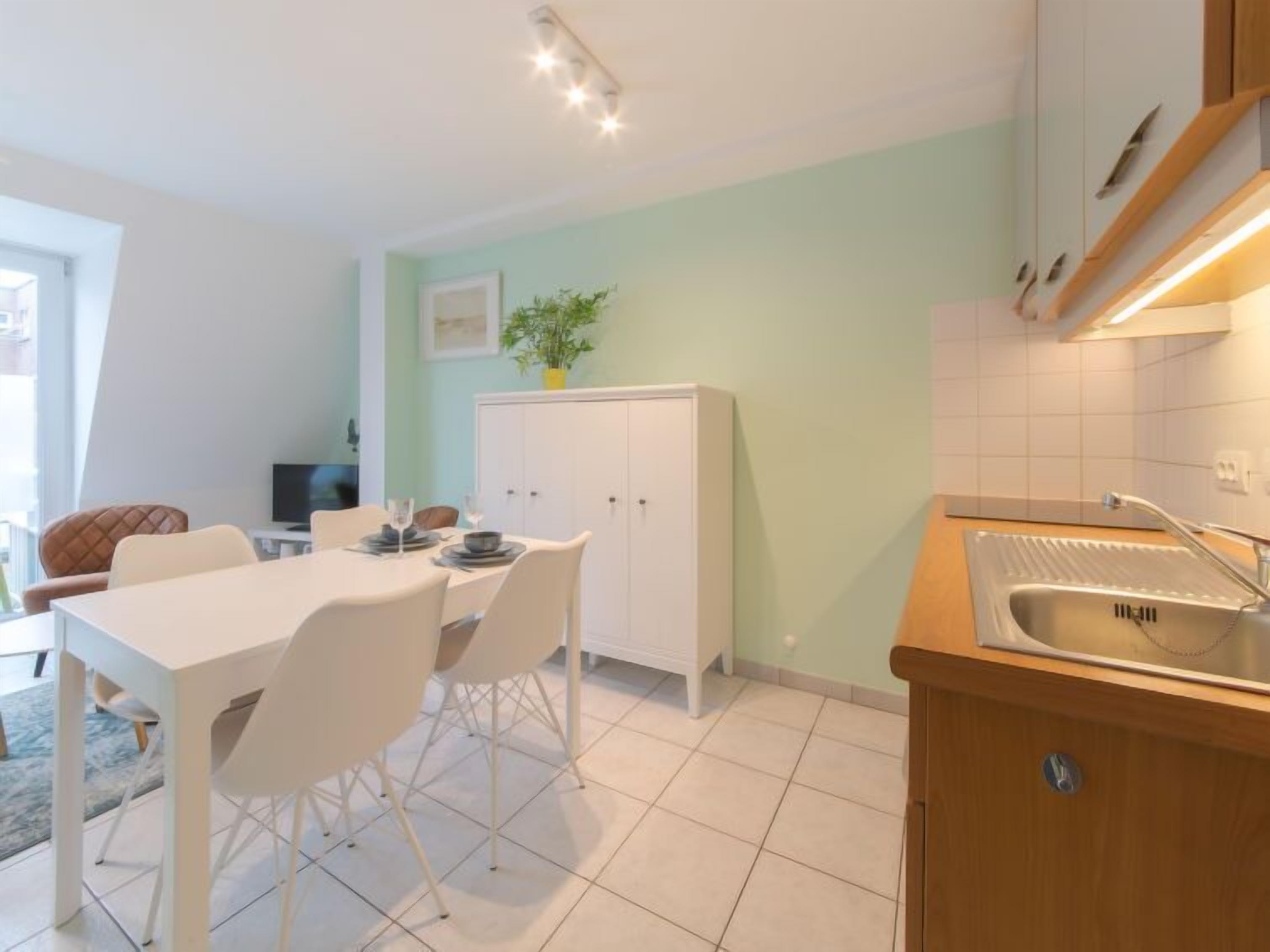 Una cucina moderna con mobili bianchi, un tavolo da pranzo con sedie e un lavello.