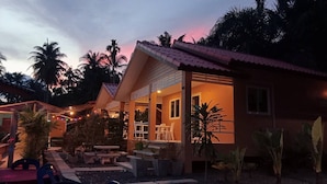 Una casa de dos pisos con un patio, mobiliario exterior y una entrada bien iluminada.