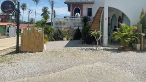Un edificio con fachada blanca, techo de paja y un letrero que indica servicios de masaje.