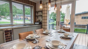 Un comedor con una mesa de madera dispuesta para cuatro personas, ventanas amplias y vistas al exterior.