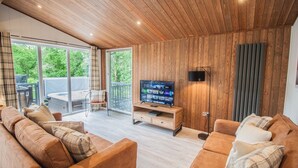 Una sala de estar moderna con techo de madera, un televisor plano grande y un juego de sofá.