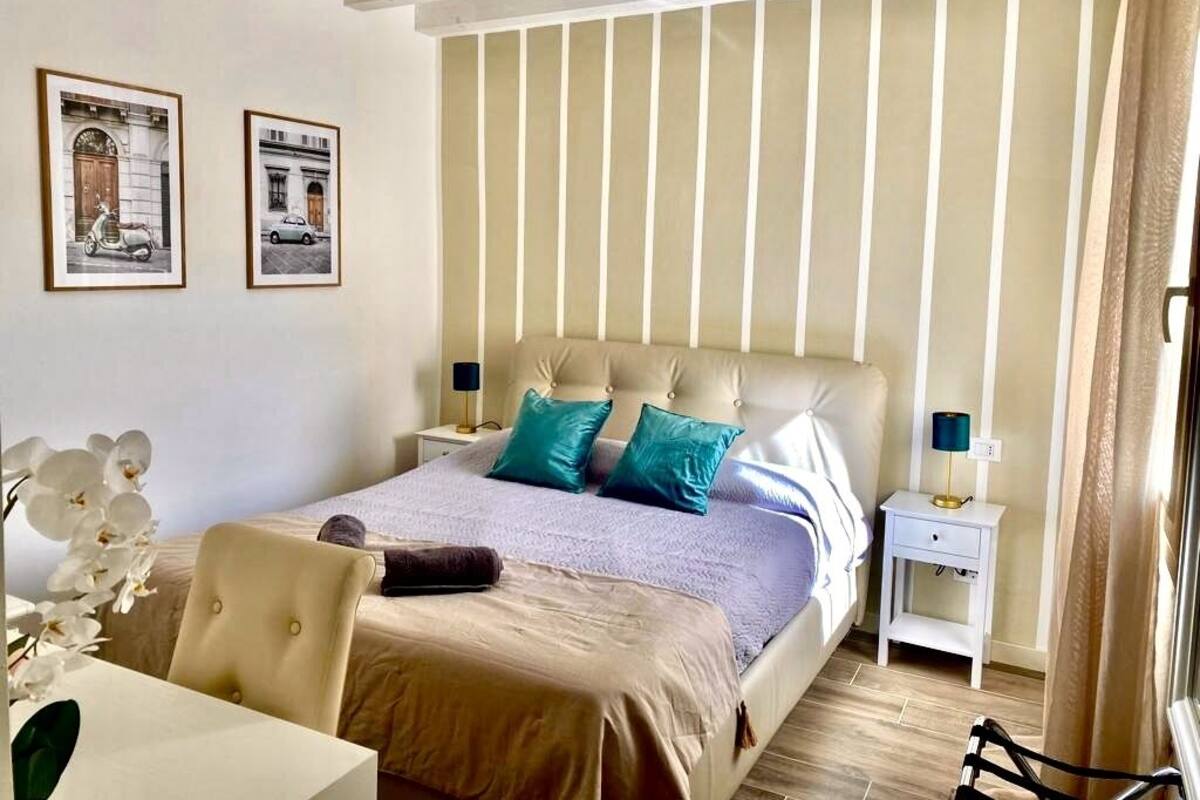 A bedroom with a bed, nightstands, a chair, and two framed pictures on the wall.
