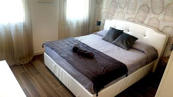 Una cama bien tendida con un cabecero blanco, una manta gris y marrón, y dos almohadas.
