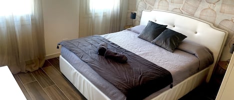 A neatly made bed with a white headboard, a grey and brown blanket, and two pillows.
