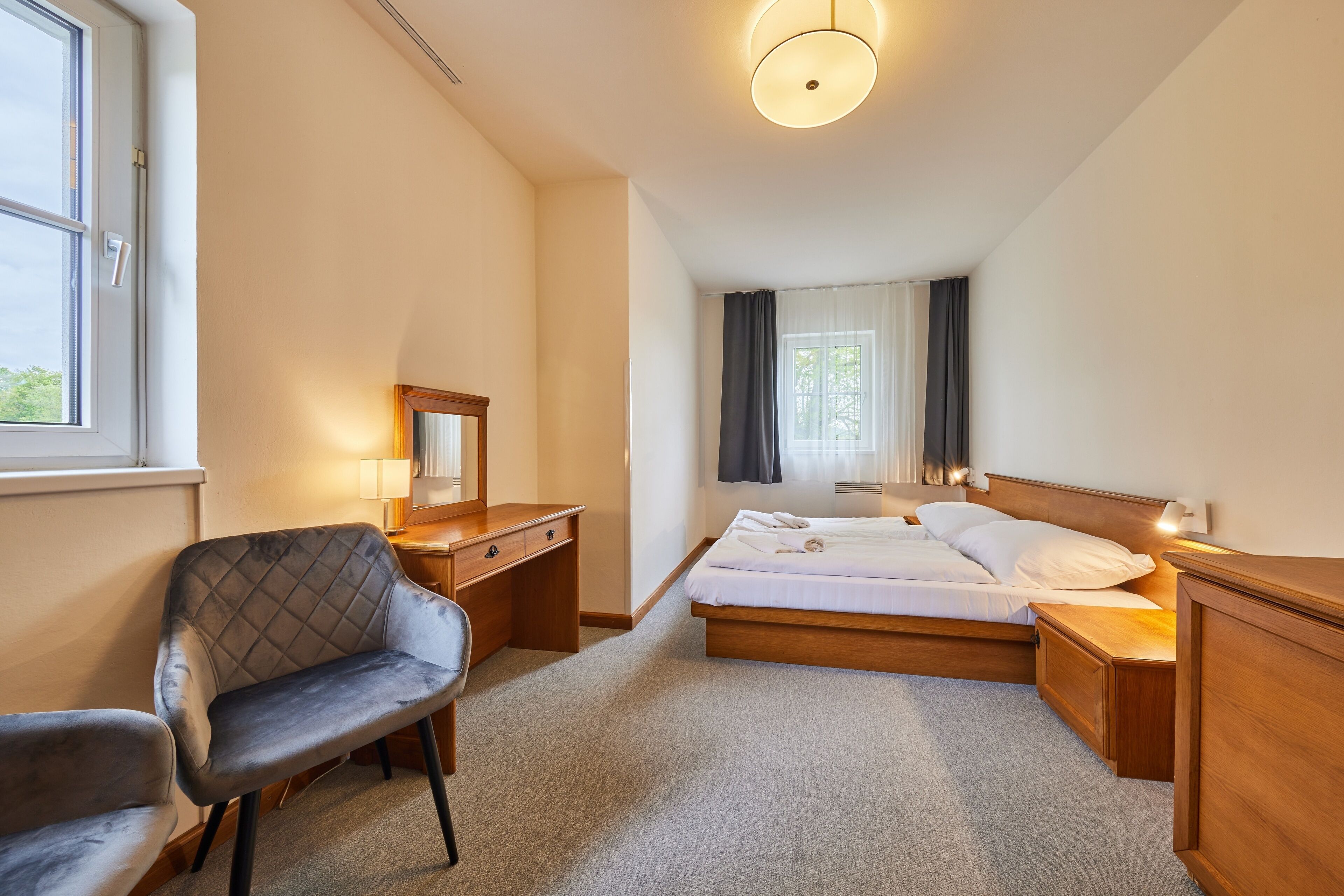 Une chambre d’hôtel avec un lit, un bureau, une chaise et une fenêtre.