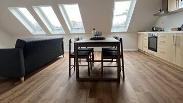 A modern kitchen with skylights, a dining table, and a sofa.