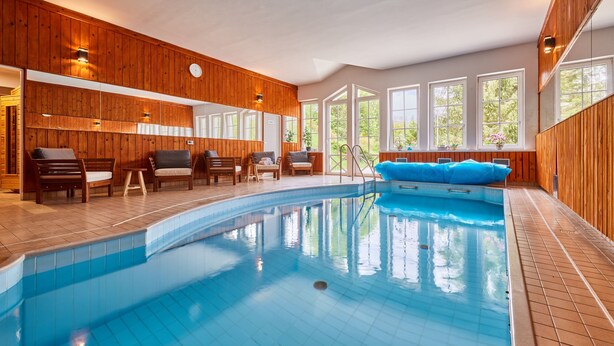 A pool area with wooden walls, a blue pool, and several lounge chairs.